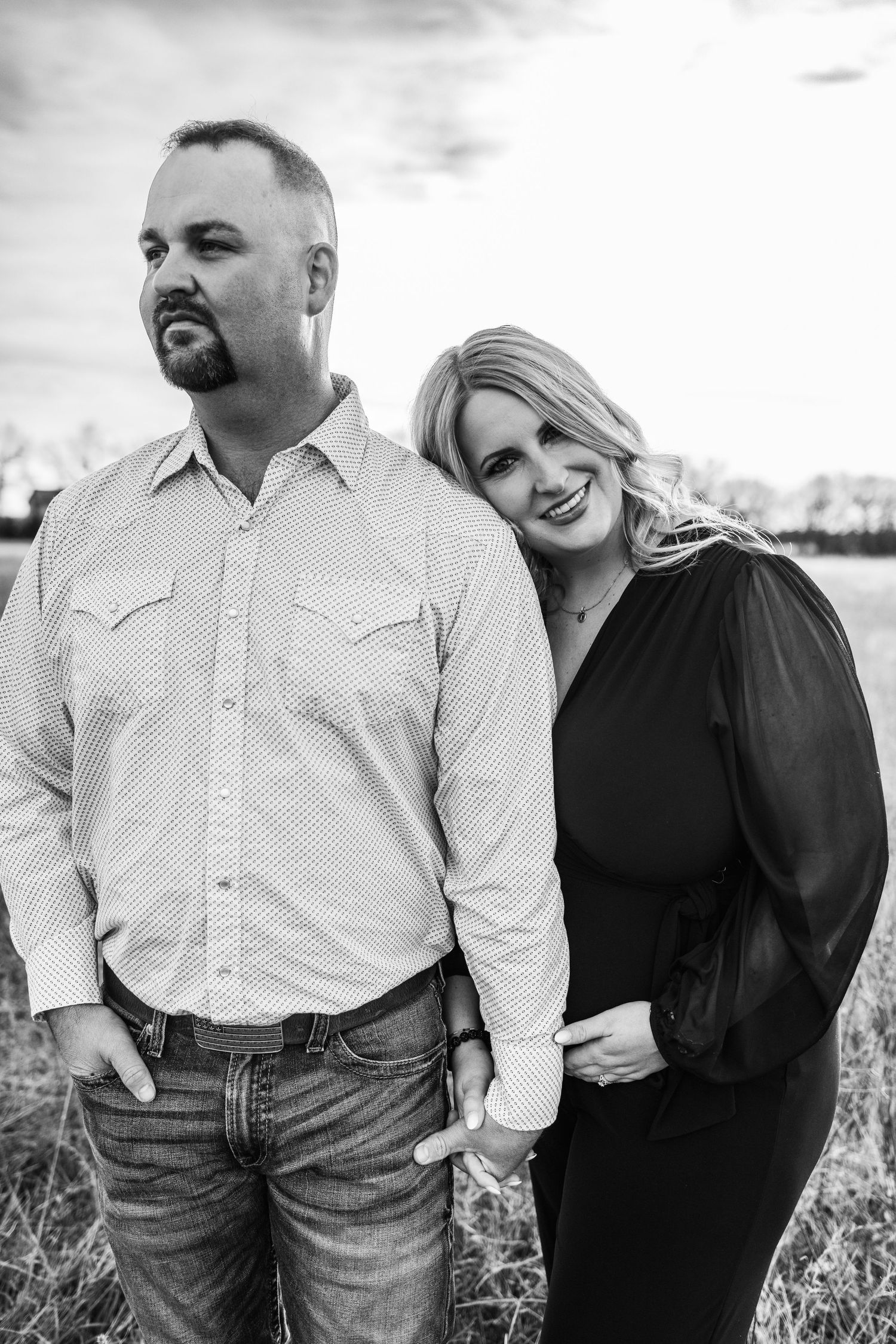 Black and white portrait of couple sharing joyful moment in field.