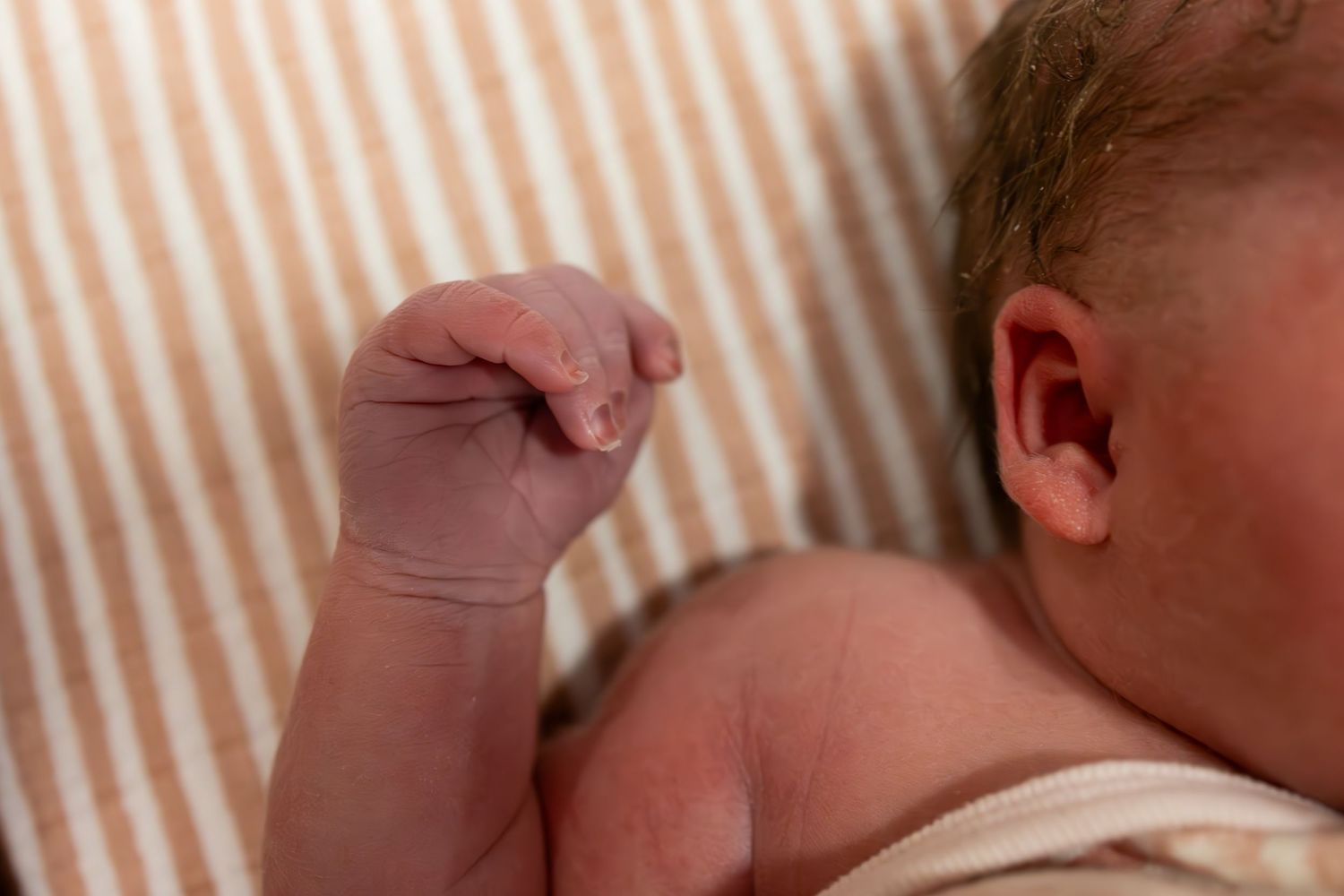 Close-up view of a sleeping newborn baby wrapped in striped blankets.