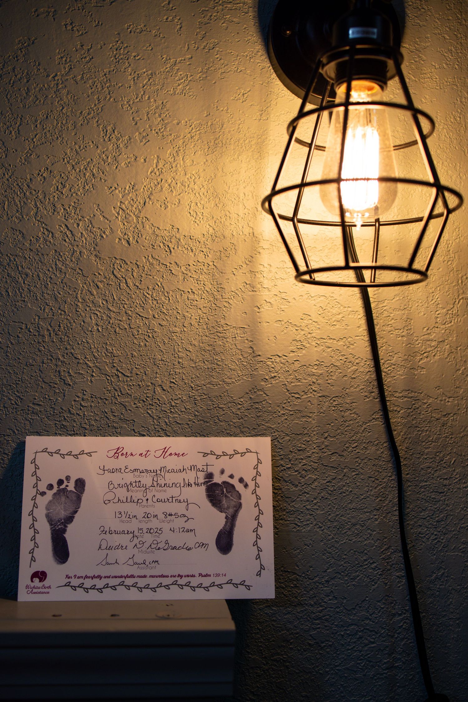 Decorative wall lights illuminating framed footprint artwork in a dimly lit room.