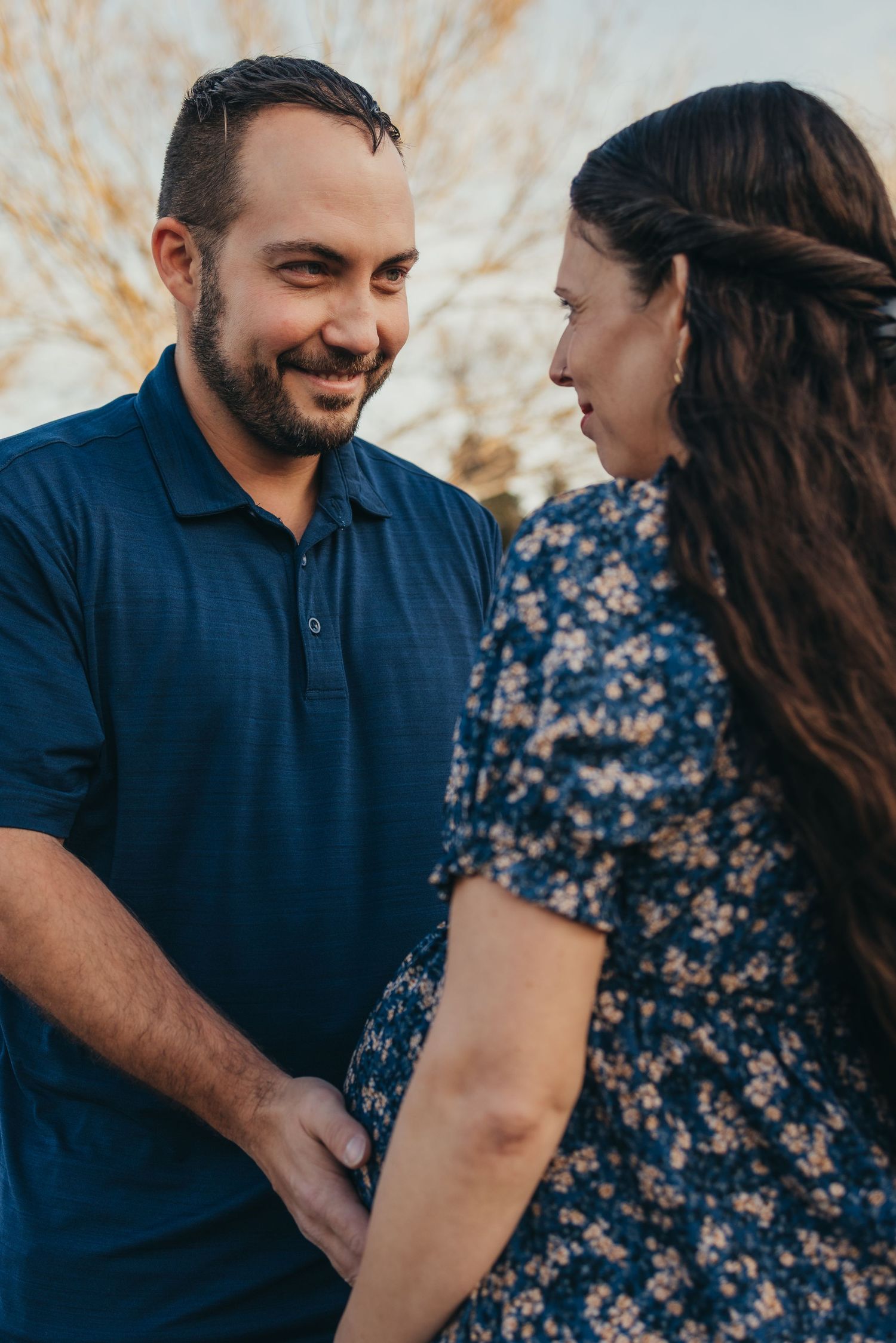 Couple sharing intimate moment outdoors wearing navy blue and floral print.