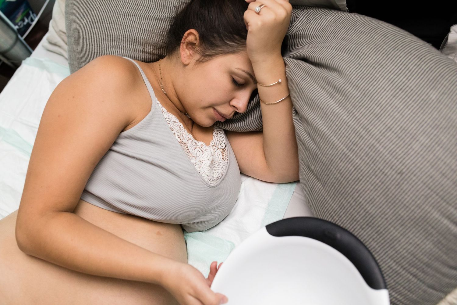 Woman lying on gray couch during labor contractions.