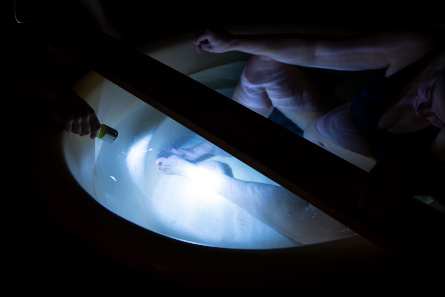 Blue medical lighting illuminates a clinical examination procedure.