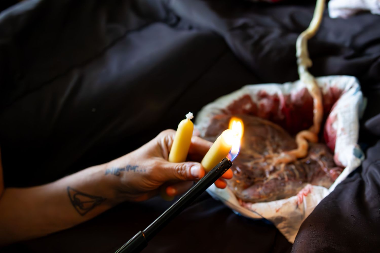 Yellow candles being lit against dark background with dramatic lighting.