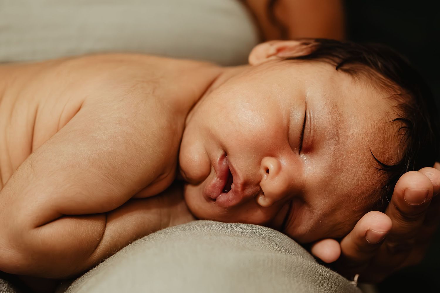 Sleeping newborn baby peacefully resting on soft surface in warm lighting.