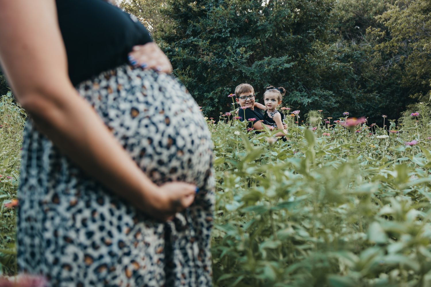 Maternity photo session in a garden with floral print dress.