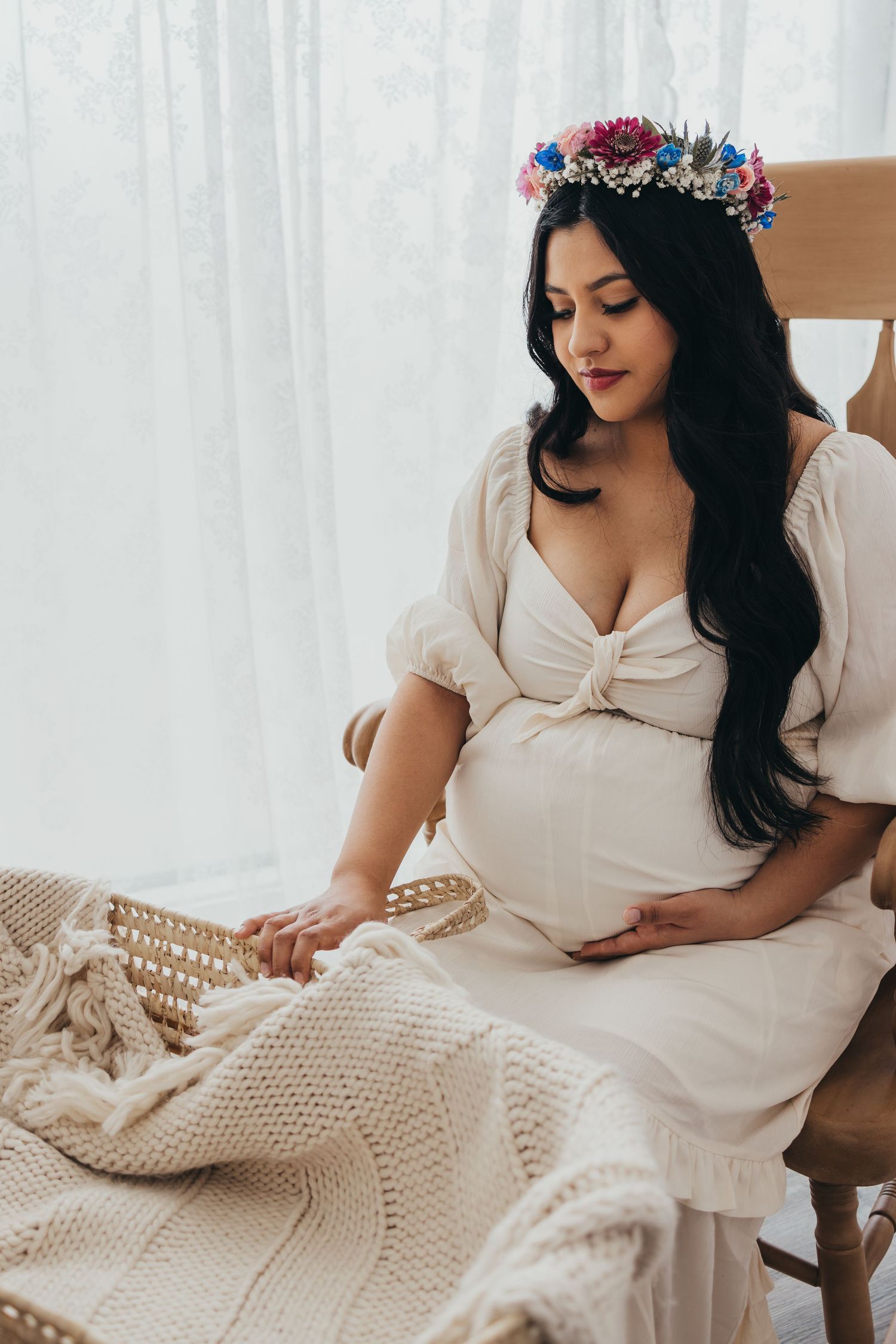 Maternity photo on bed with knit blanket and floral crown.