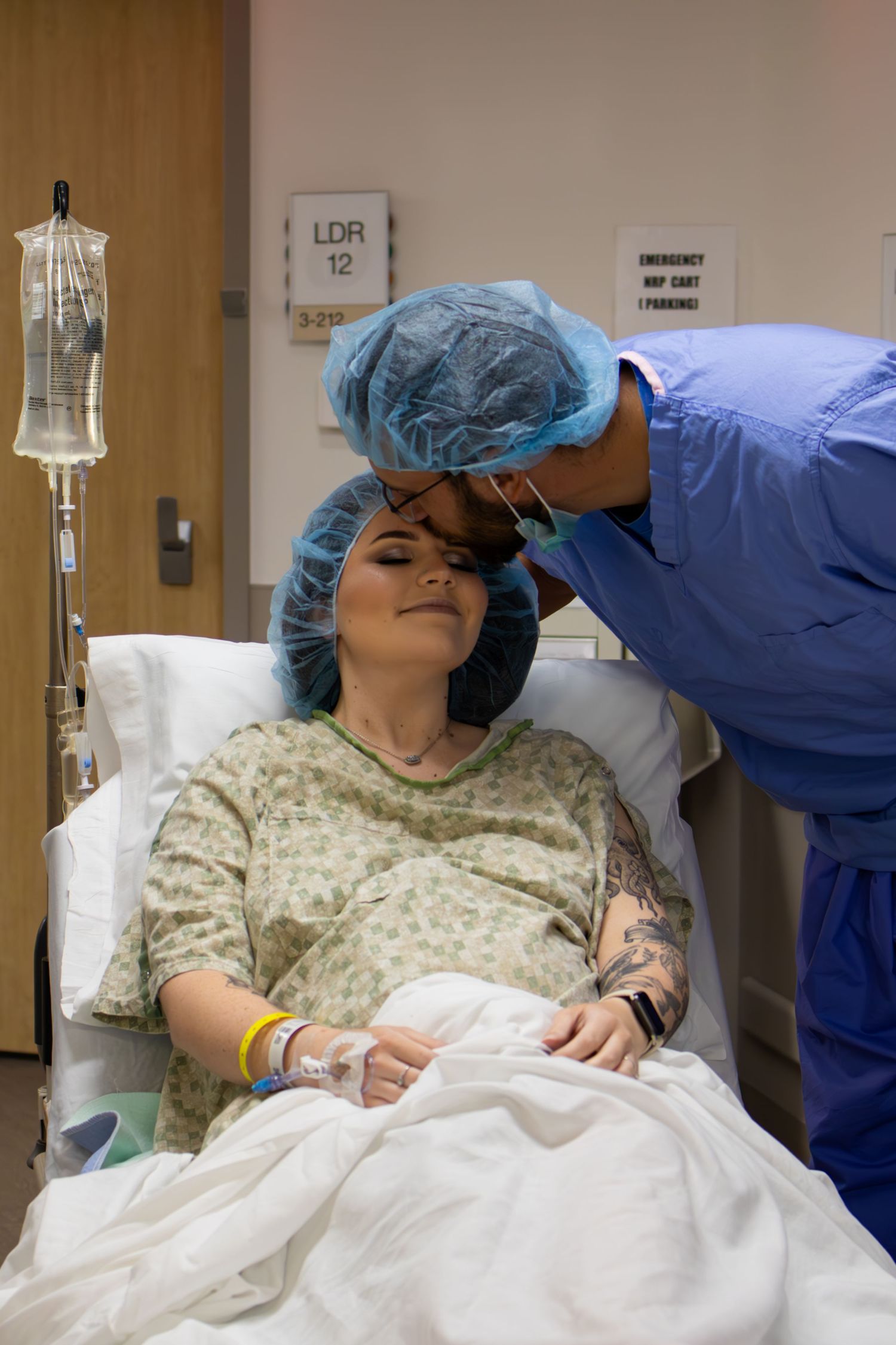 Patient in hospital gown receiving care from medical staff wearing blue scrubs.