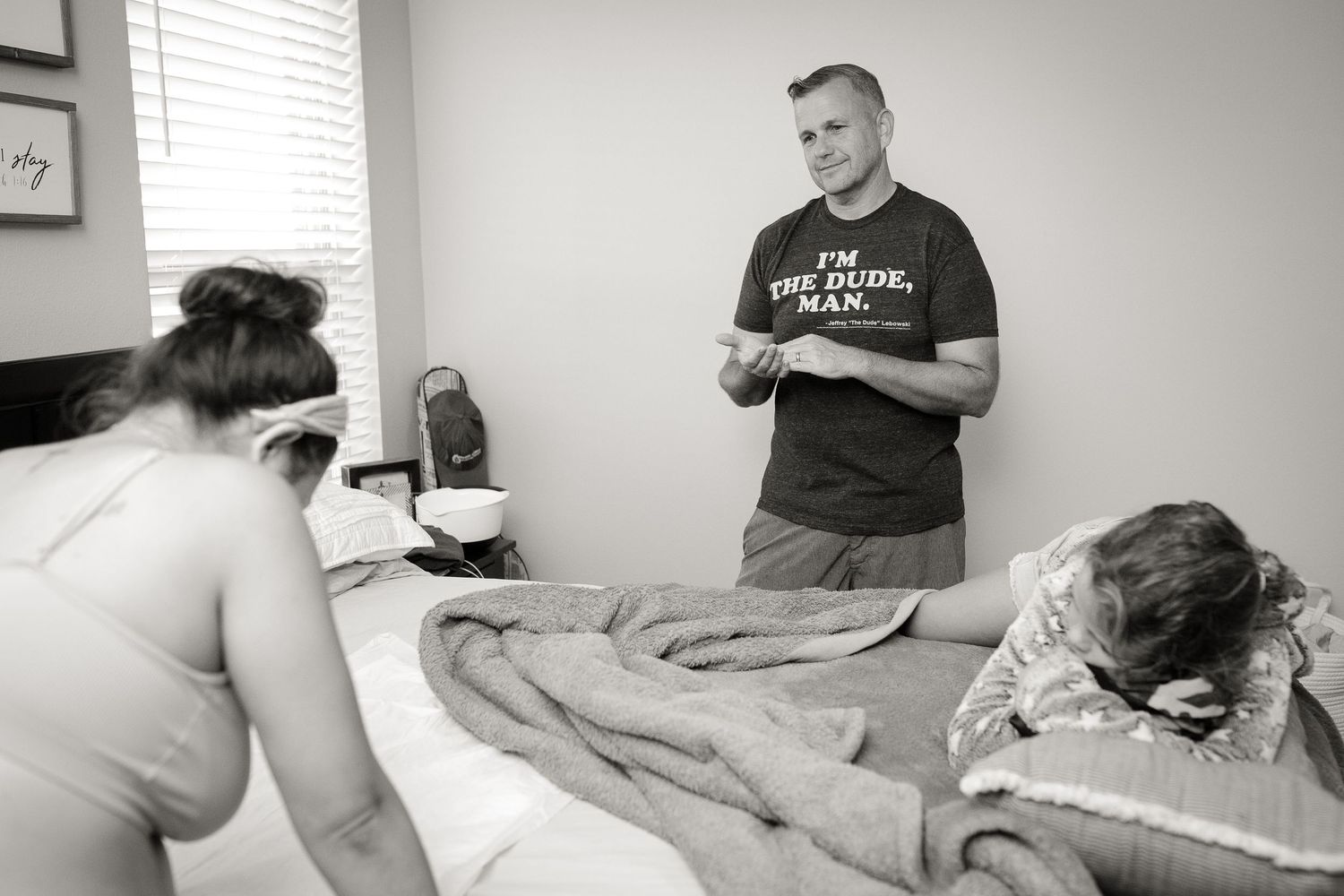 Couple preparing for childbirth in bedroom with white bedding.