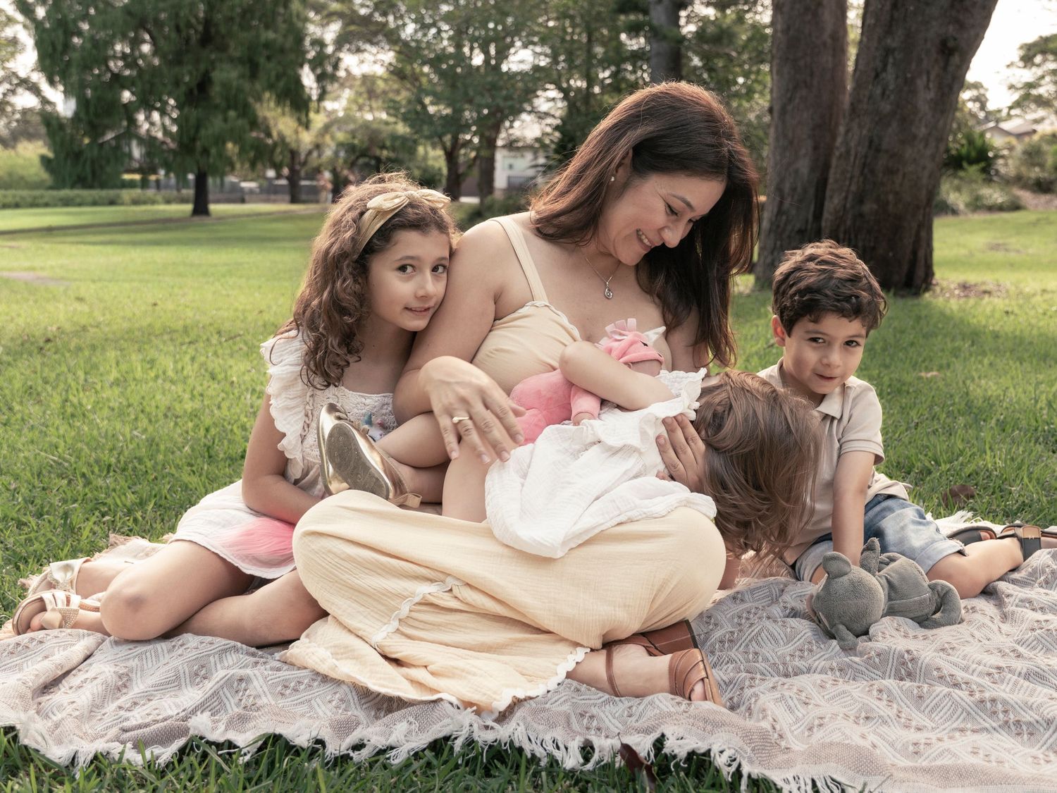A series of connected images showing a family relaxing on a blanket in a park with their pet rabbit.