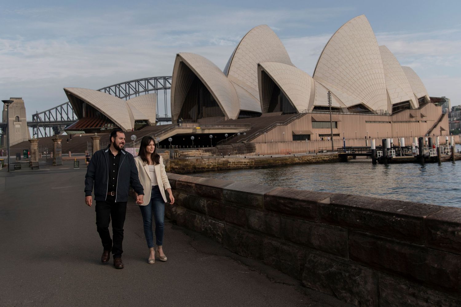 A couple near the iconic Sydney Opera House on a cloudy day.