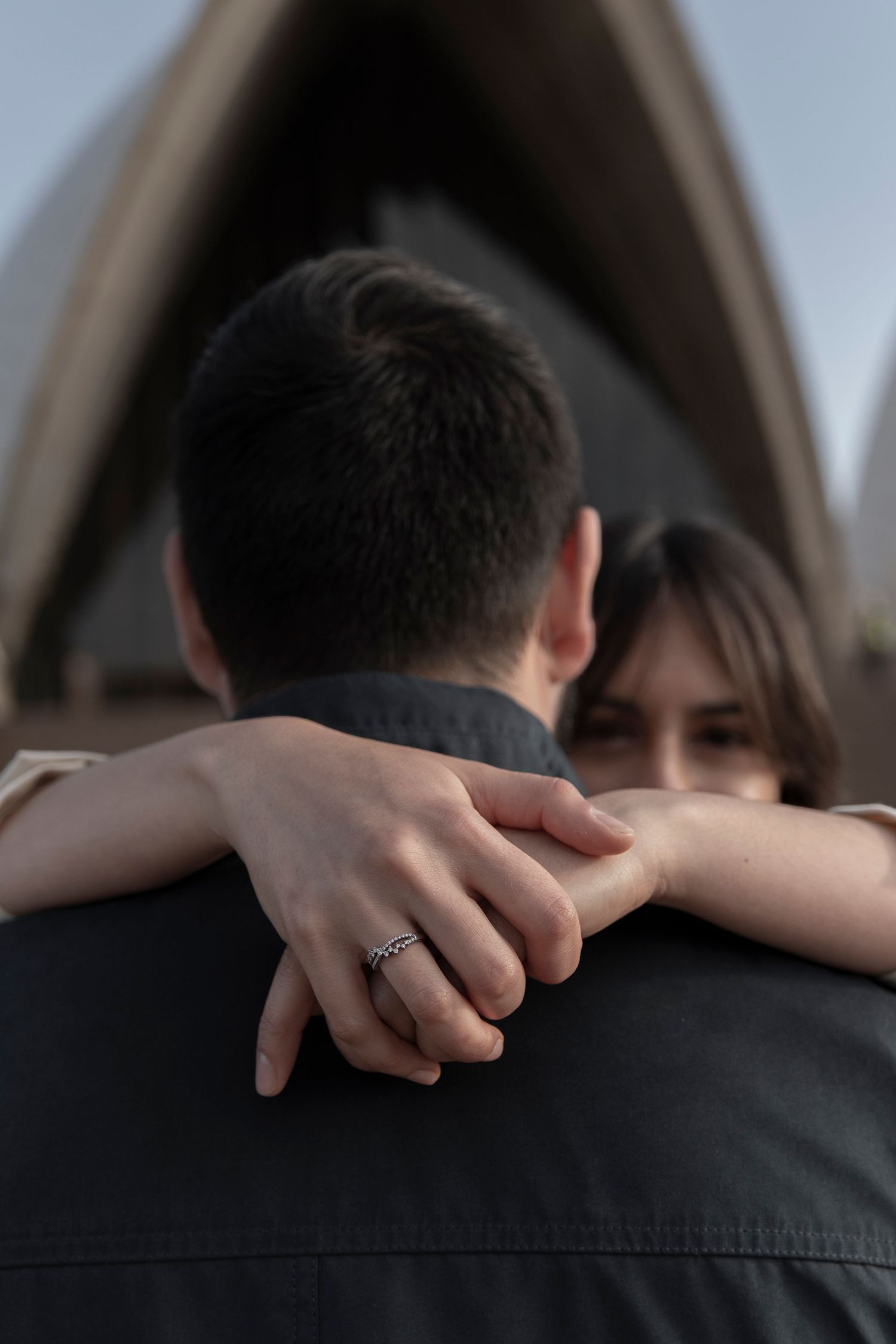Intimate engagement photo showing couple embracing near Sydney Opera House.