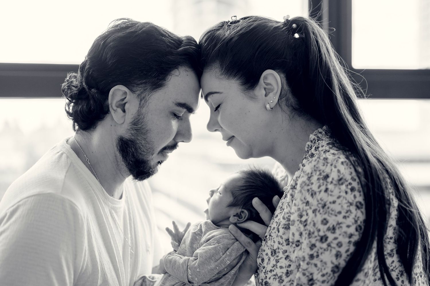 A tender black and white series showing a couple embracing their newborn baby.