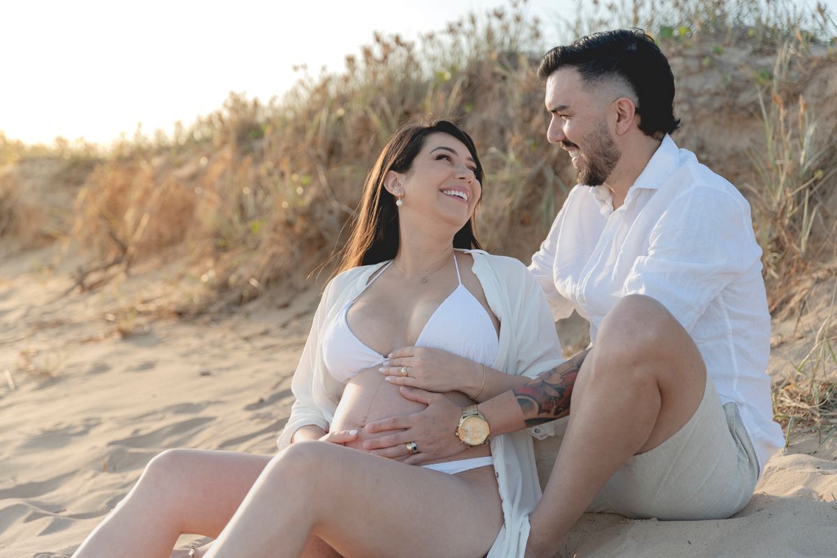 Couple relaxing together on sandy beach during sunset.