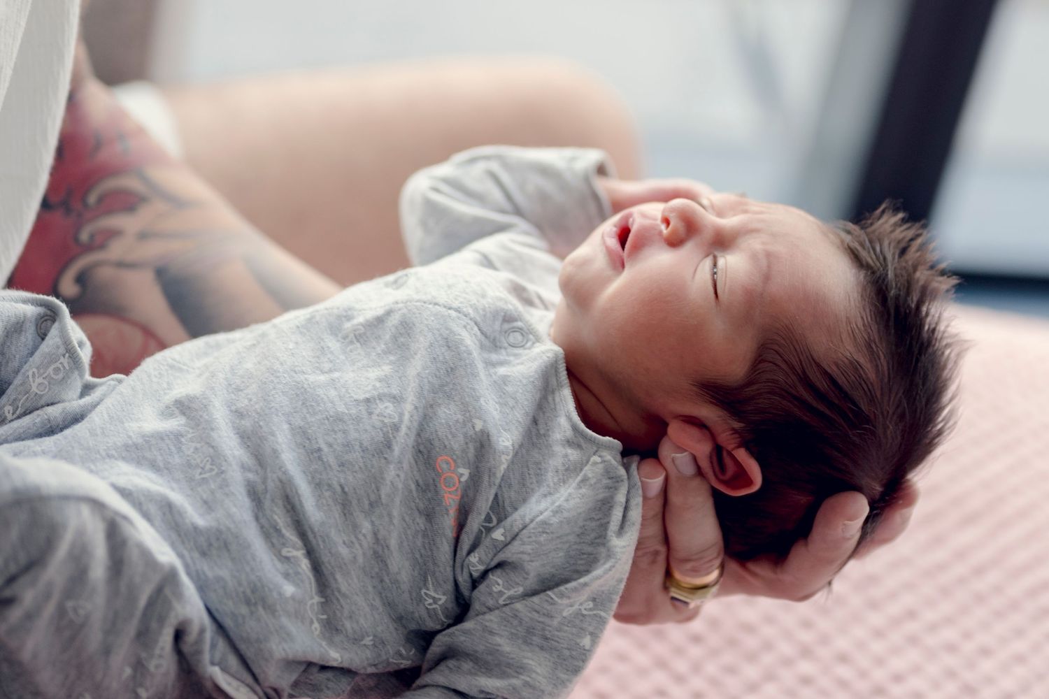 Baby sleeping peacefully on pink bedding in natural light.