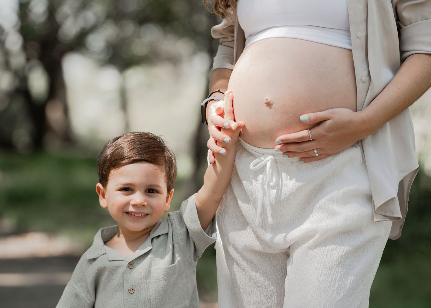A series of pregnancy progression photos showing a growing baby bump in white clothing against an outdoor background.