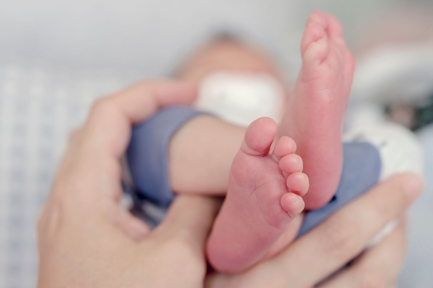 Gentle hands holding and caressing newborn baby feet.