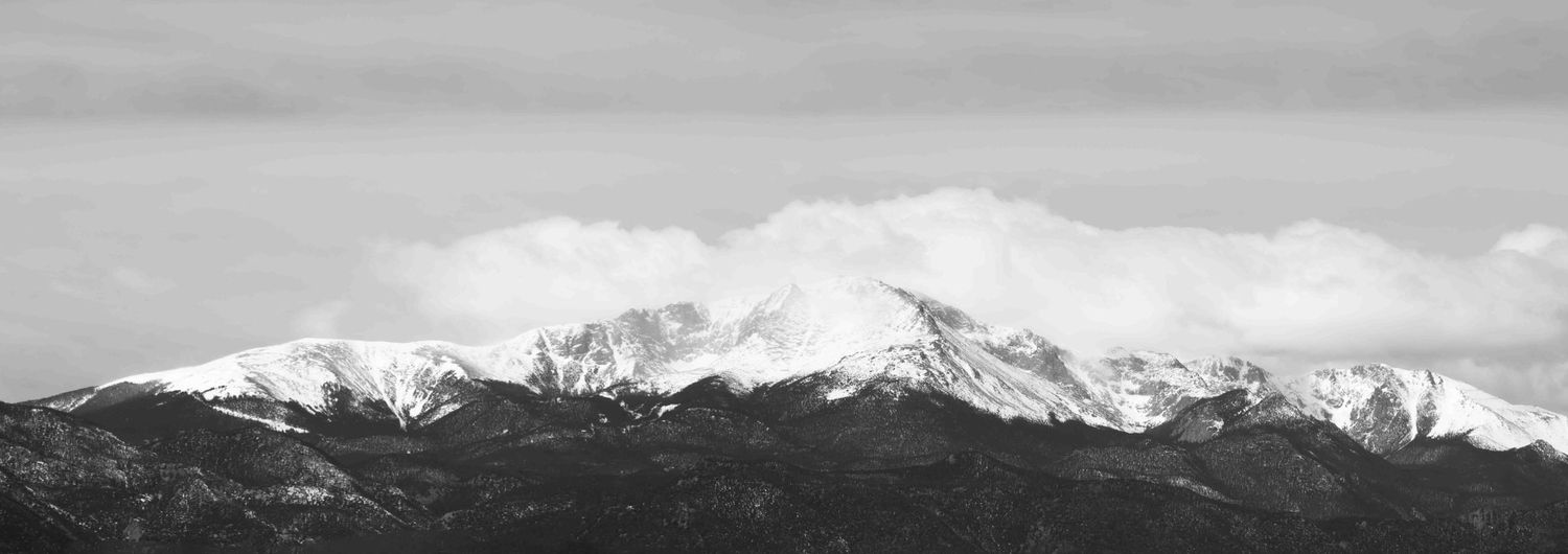Dramatic black and white mountain range landscape with snow-capped peaks.