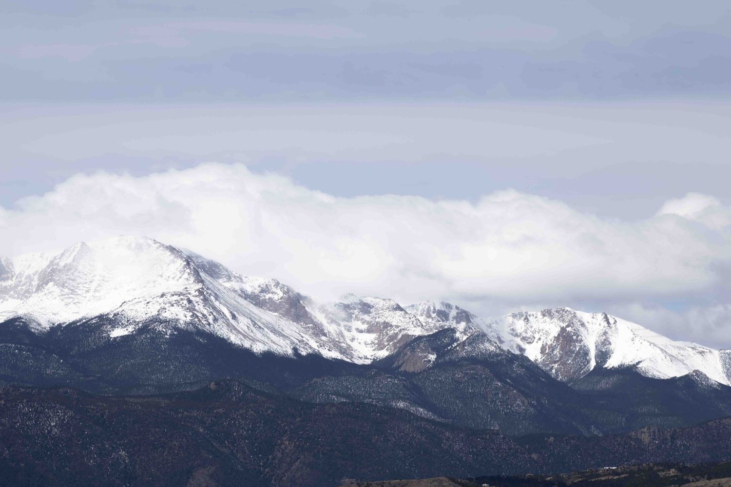 Snow-covered mountain peaks against cloudy sky in winter landscape.