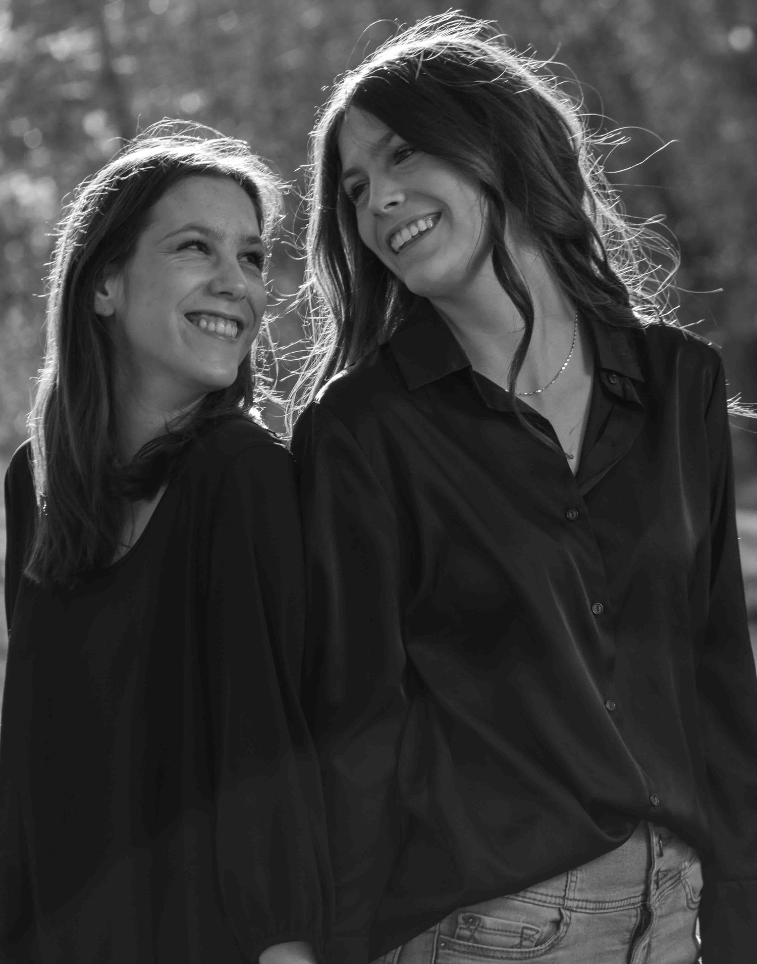 Two friends sharing a candid laughing moment together in black and white photography.