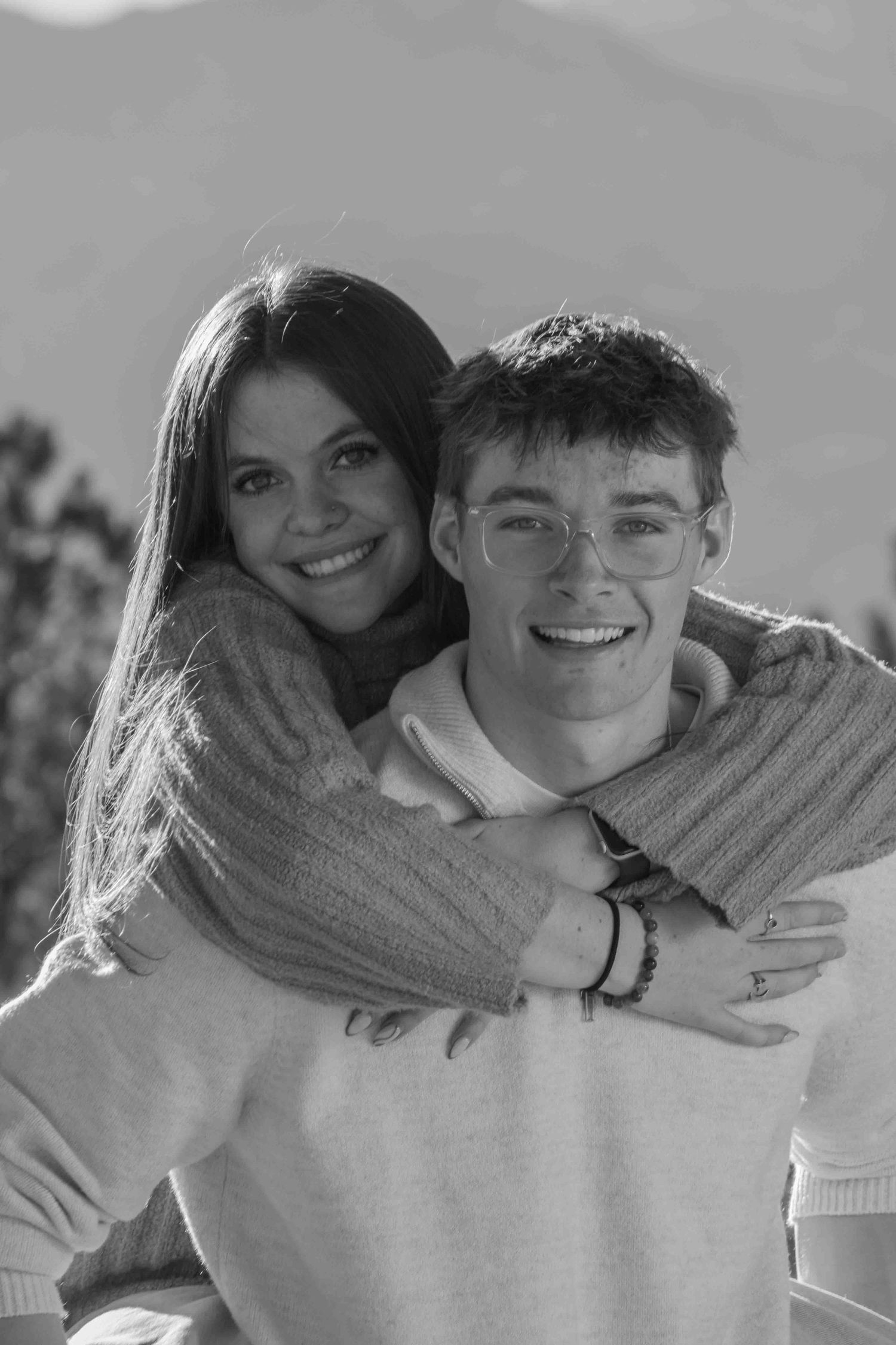 Black and white portrait of couple embracing and smiling in casual outfits.