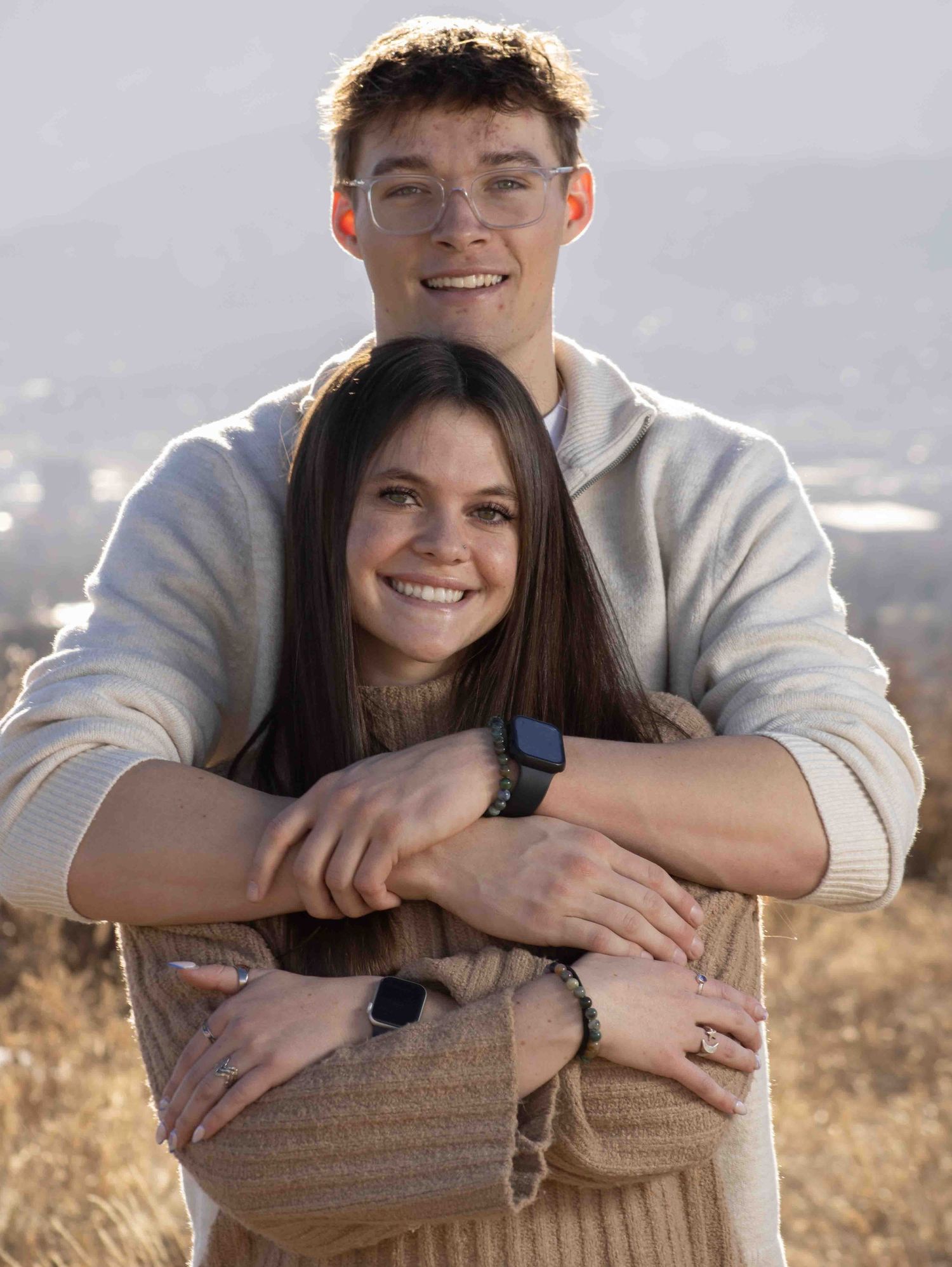 Cozy couple portrait session with warm sweaters and casual styling on hilltop.