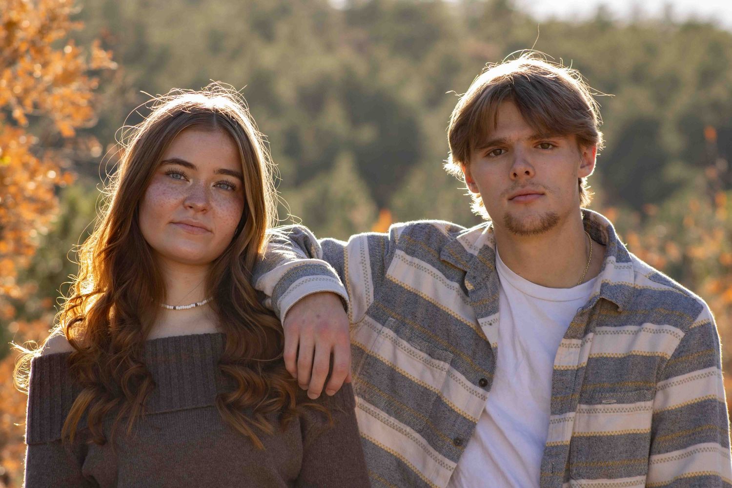 Couple embracing in casual outfits against warm autumn sunset lighting.