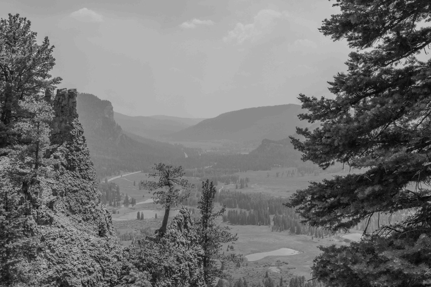 A black and white landscape view of mountain valleys and forested hills.
