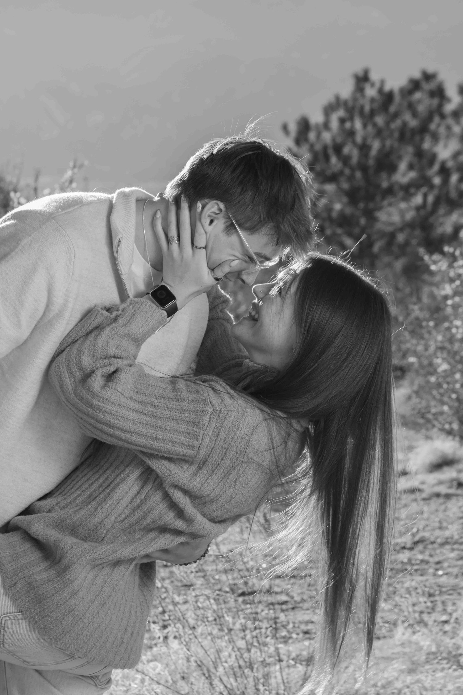 A romantic black and white portrait of a couple sharing an intimate moment outdoors.