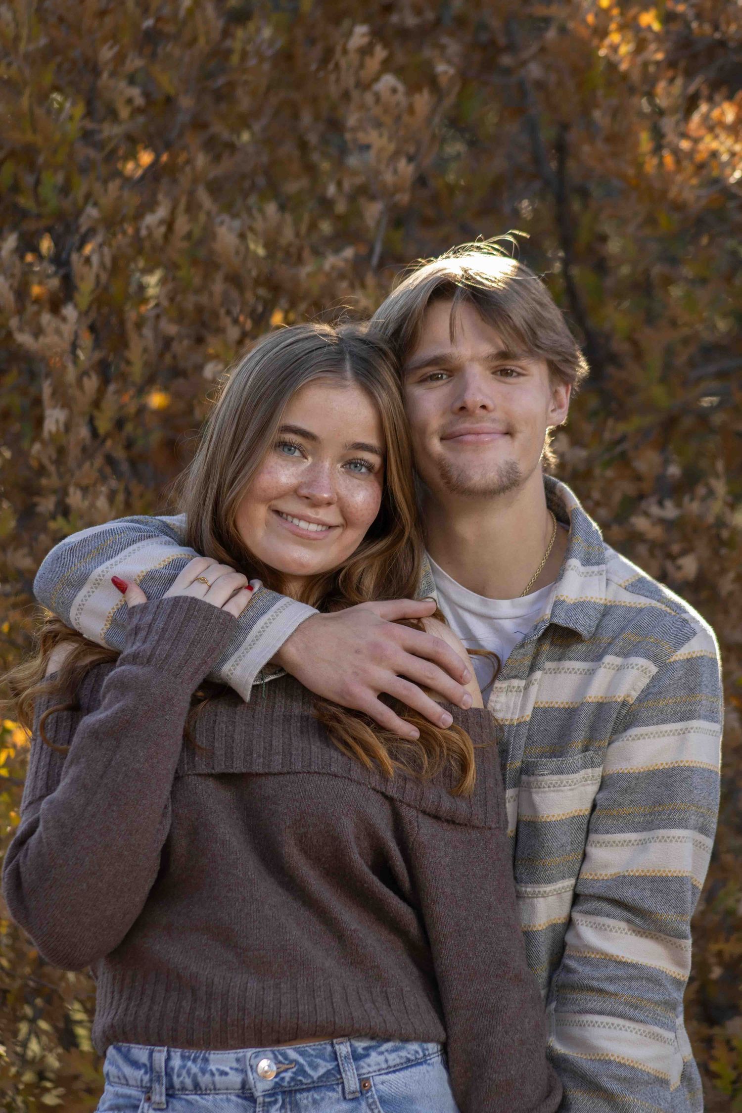 A couple shares an intimate moment outdoors wearing coordinated casual outfits in autumn.