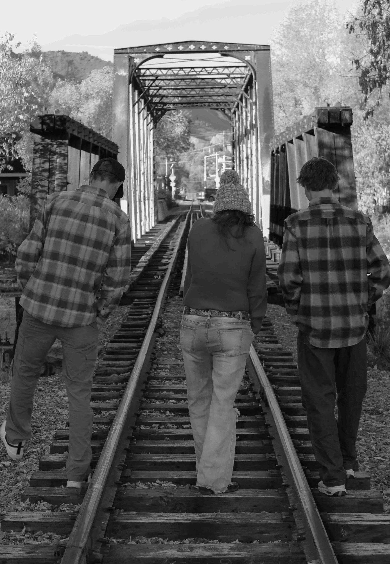 People walking along an old railroad bridge in black and white, creating a sequence of similar perspectives.