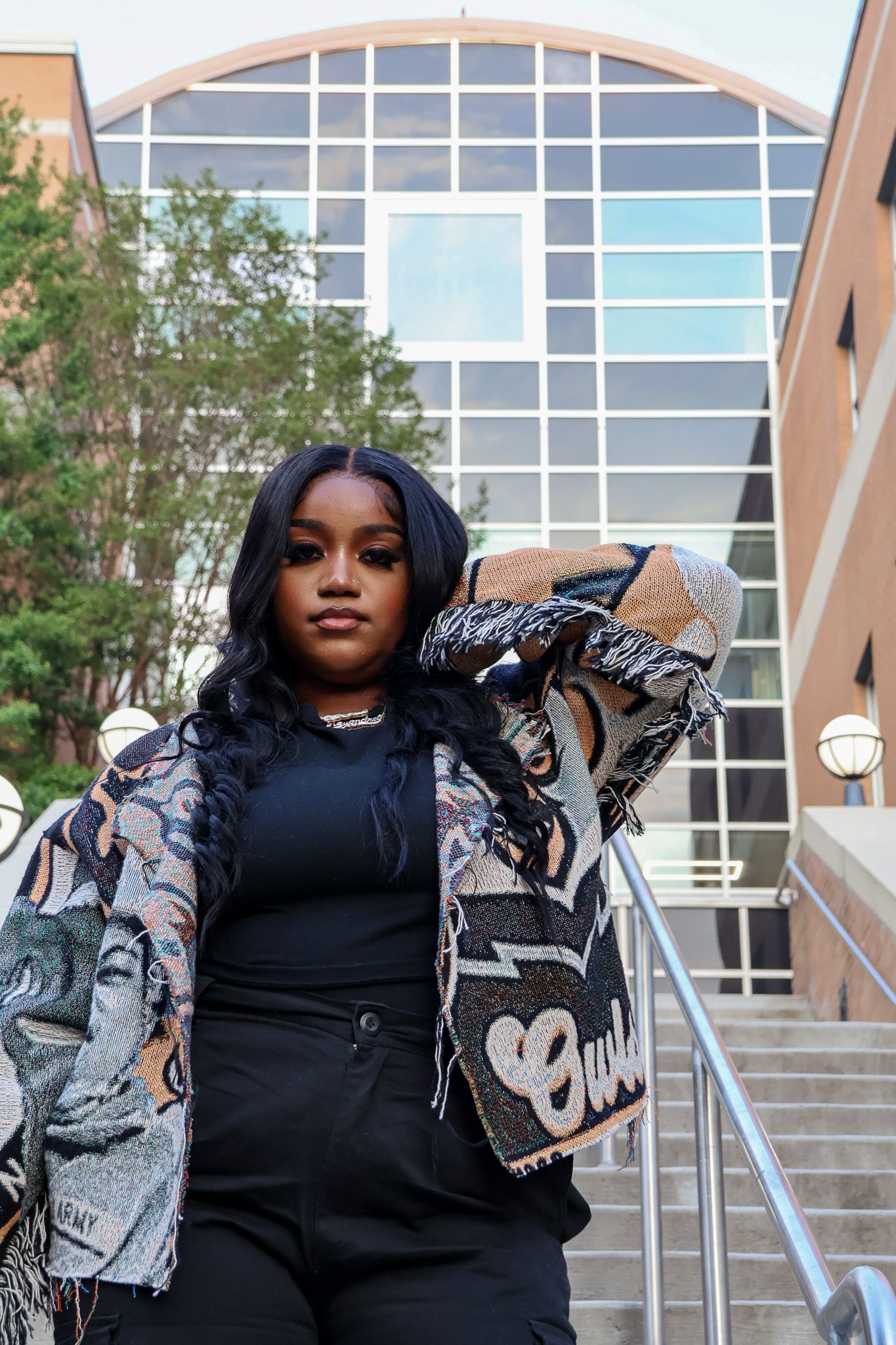 A fashionable outfit featuring a monochrome base with a patterned jacket in front of a modern building.