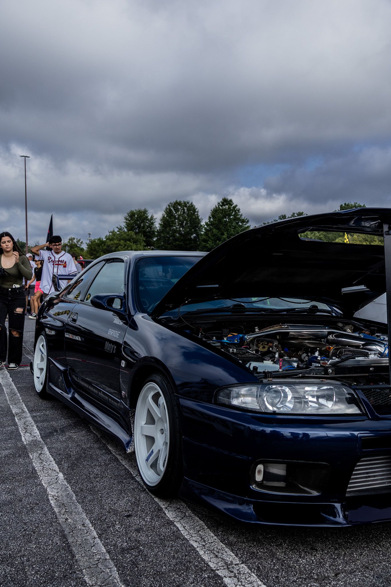 Midnight blue Nissan Skyline GTR with hood open at a car meet.