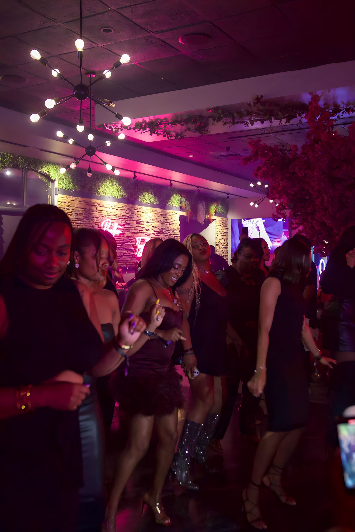 Party-goers dancing in a nightclub with decorative lighting and stone wall features.