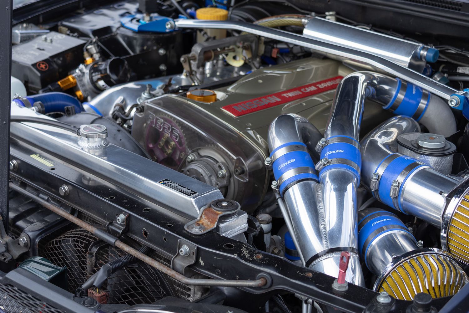 Modified performance engine bay with blue intake piping and aftermarket components.