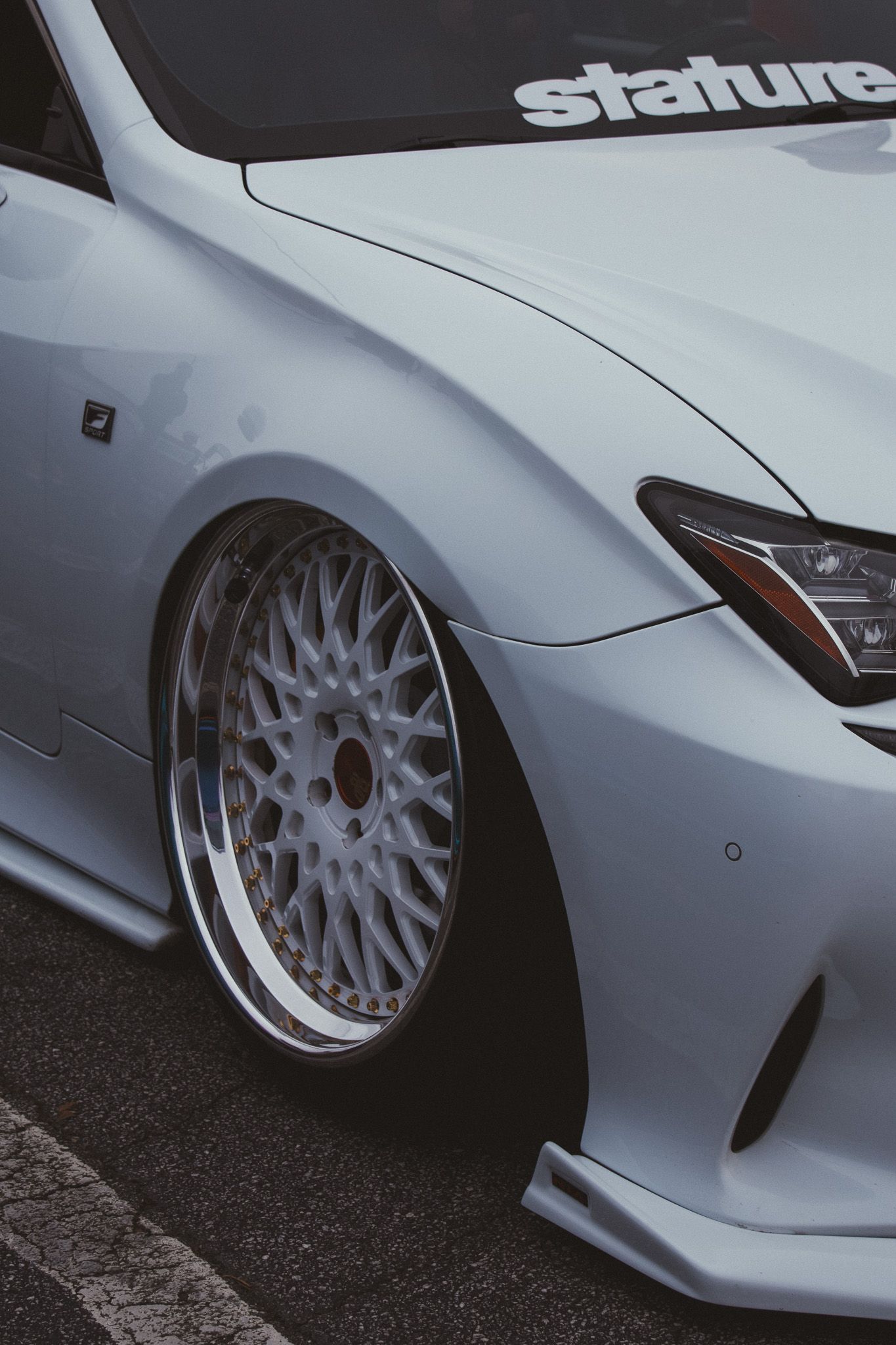 White lowered car with custom mesh wheels and Stature decal.