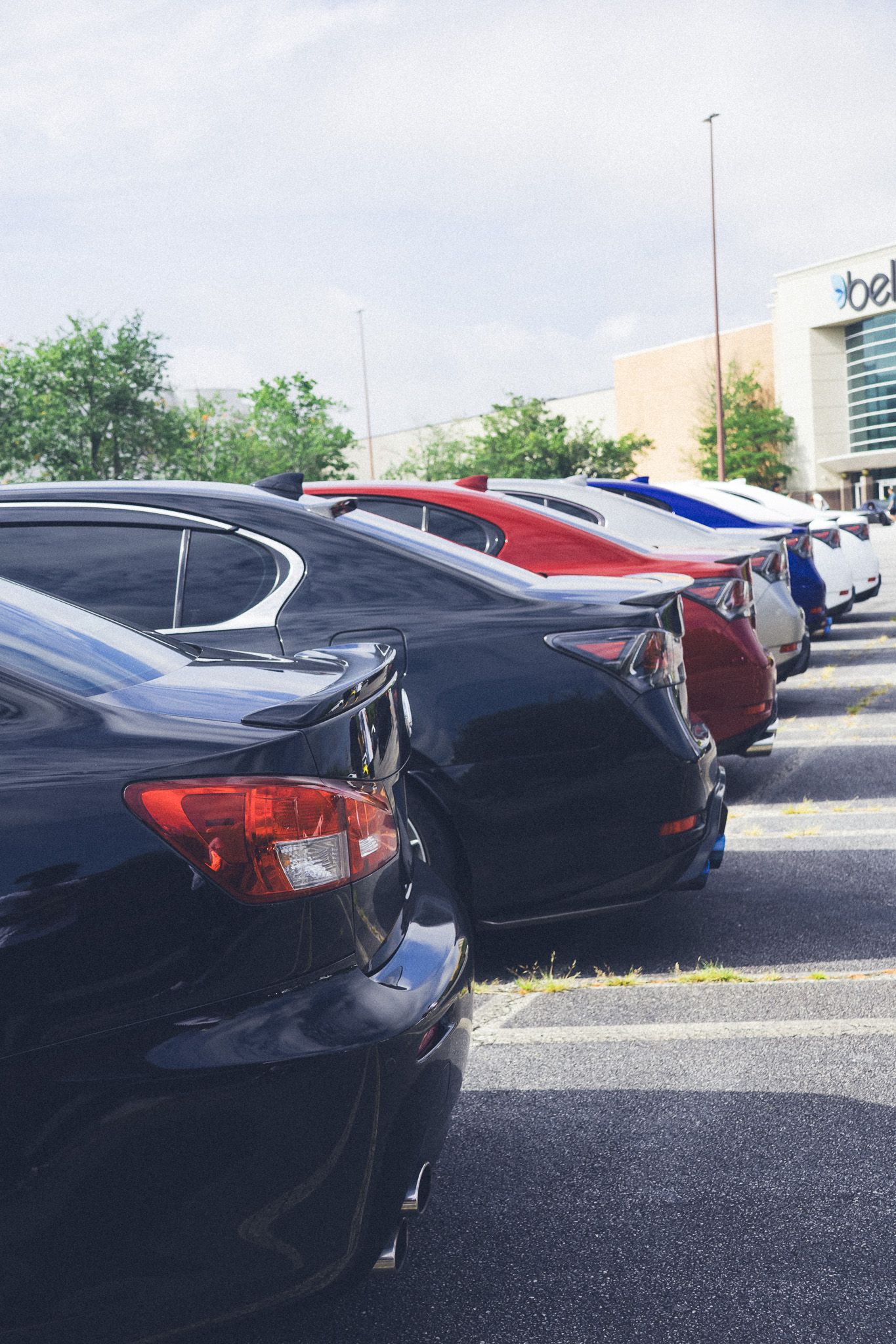 Row of luxury cars parked diagonally in a commercial parking lot.