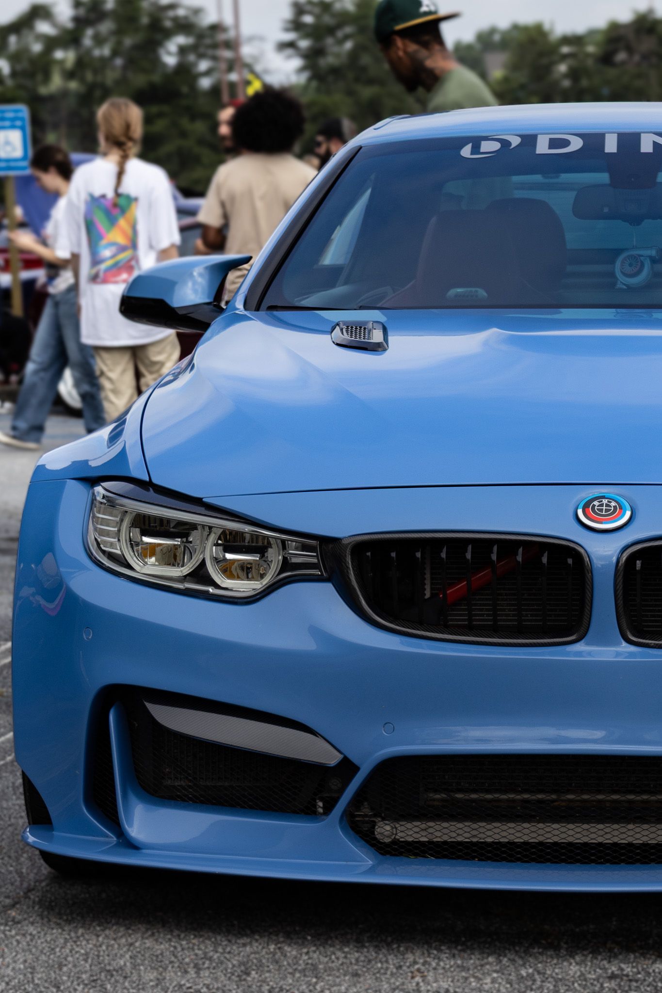Close-up of bright blue BMW M4's aggressive front end design with signature kidney grilles.