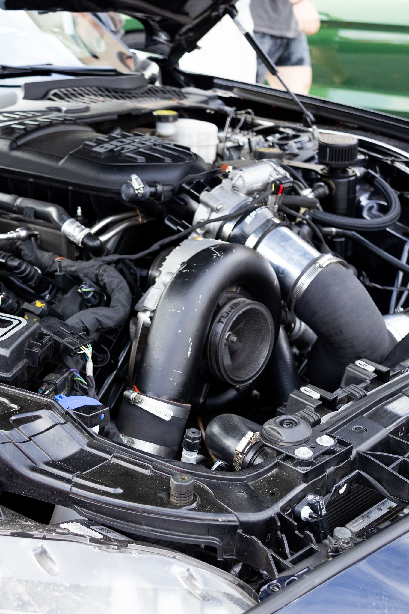 Under the hood view of a performance car engine bay showing large turbocharger and intake system.