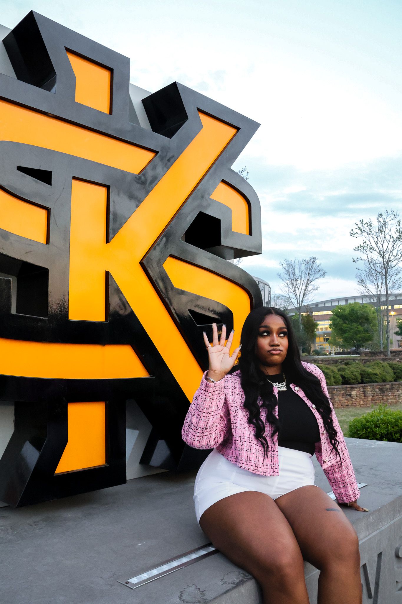 Trendy outfit captured in front of large yellow and black Kennesaw University sign.