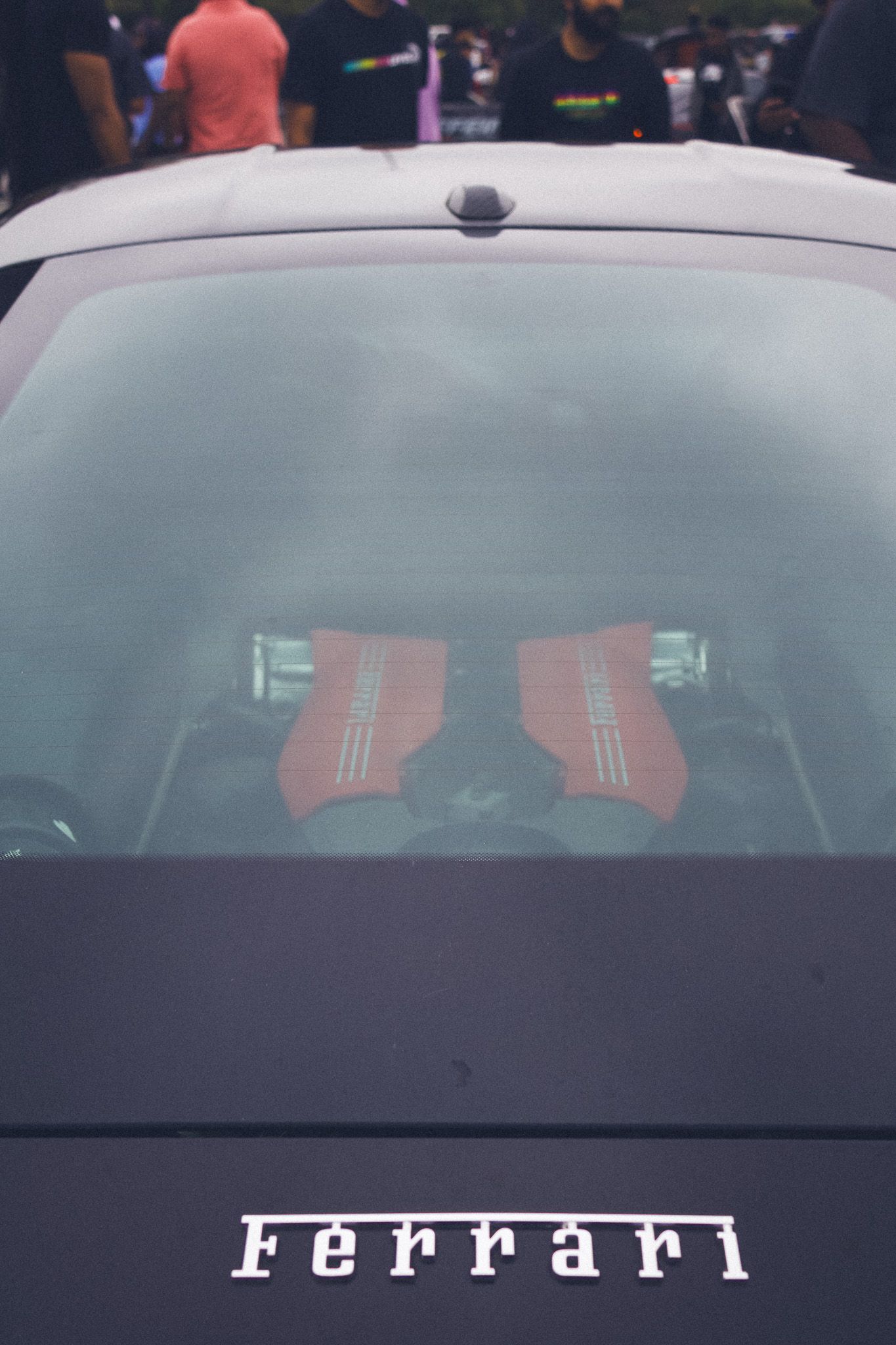 Red Ferrari racing seats visible through rear window with Ferrari badge on black exterior.