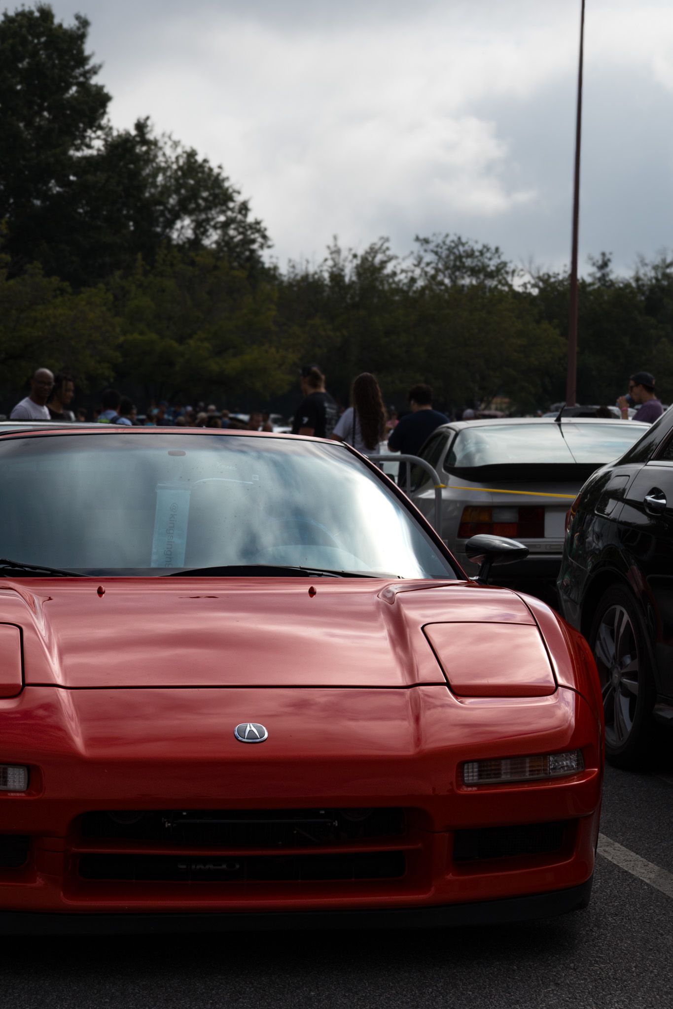Red Acura NSX front view showcasing iconic pop-up headlights in parking lot setting.