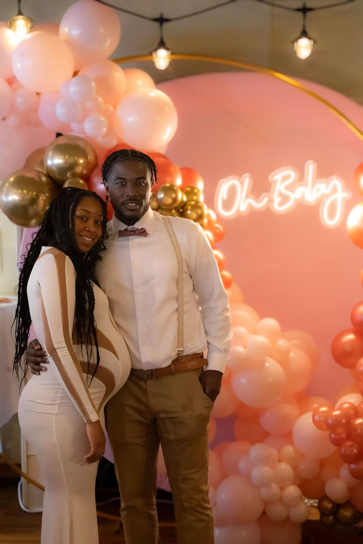 Romantic celebration setup with pink and gold balloons and neon sign lighting creating an elegant party atmosphere.