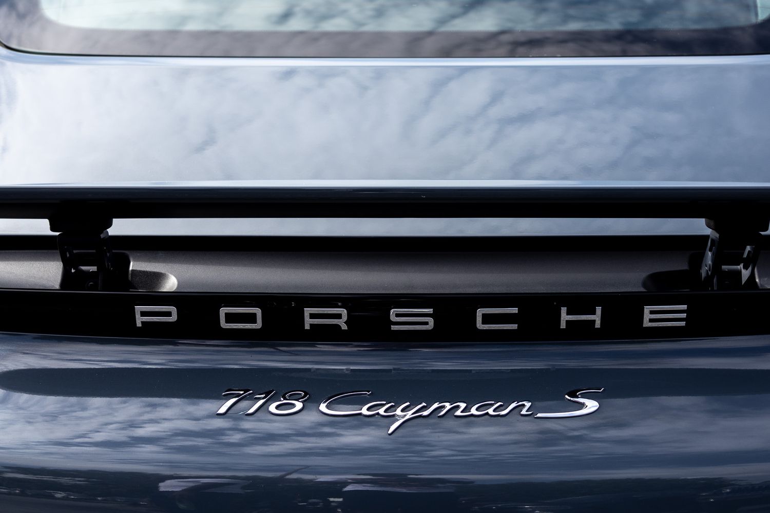 Close up detail shot of Porsche Cayman S badge and trim on black paint.