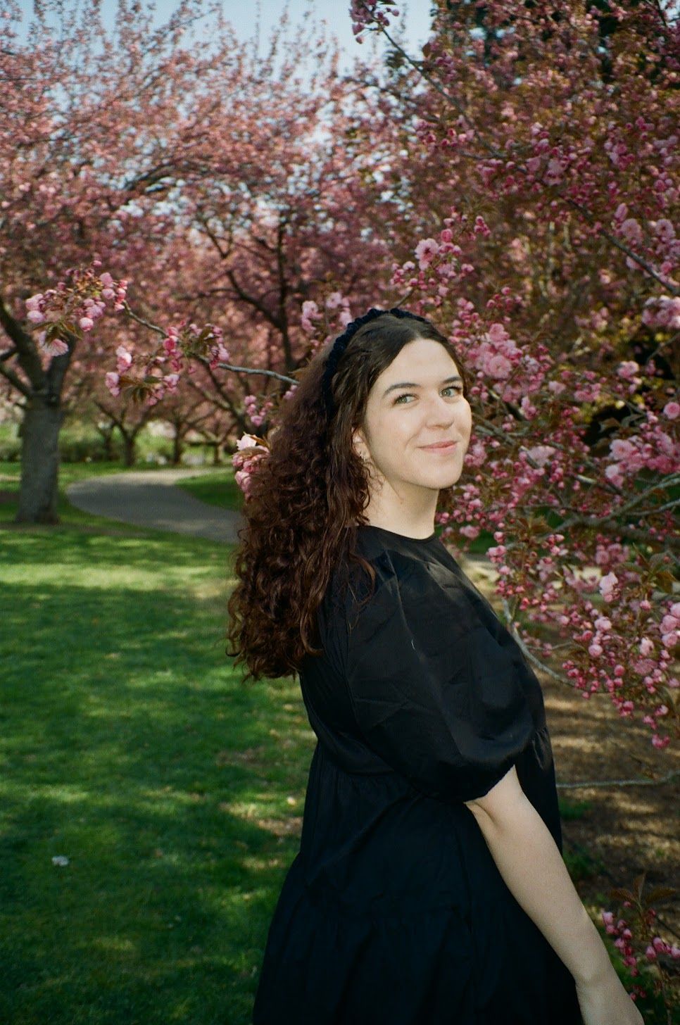 film photo of woman in the Brooklyn Botanical Garden looking at camera smiling during a creative portrait session