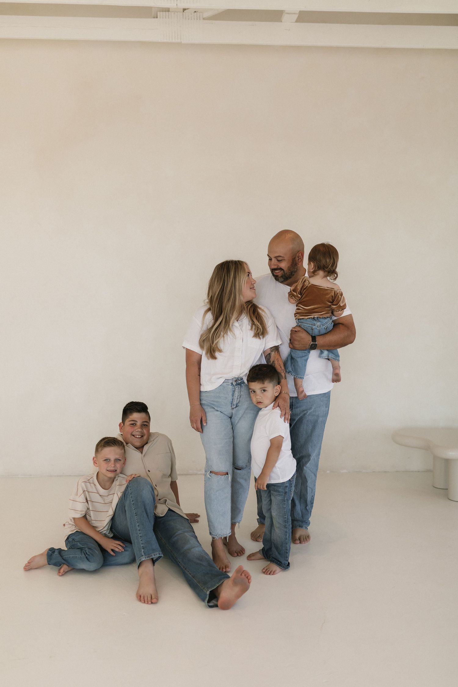 A casual family portrait series in light tones showing tender moments of connection and love on a neutral backdrop.