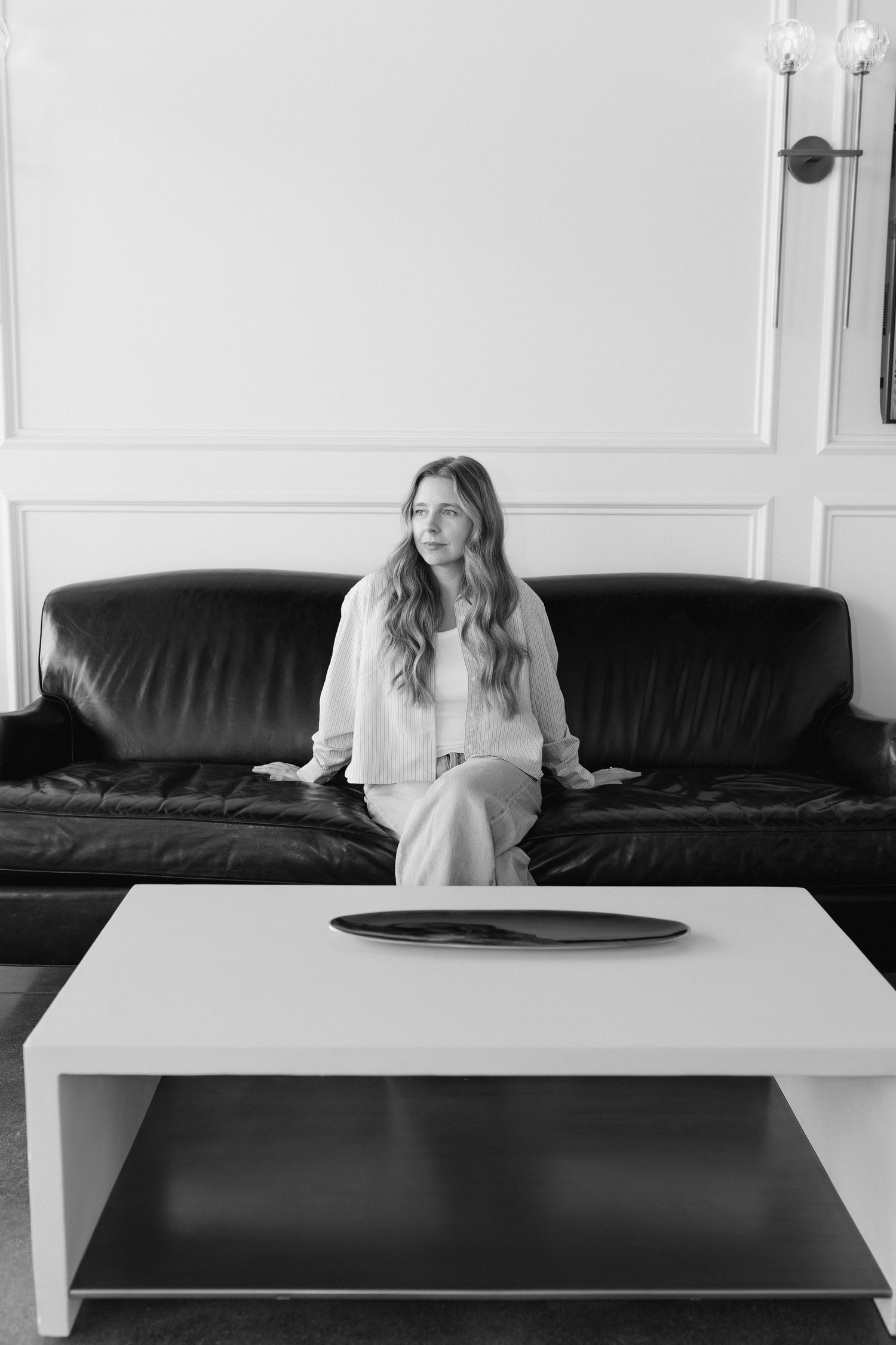 A series of black and white images showing someone sitting and stretching on a black couch against a white wall.