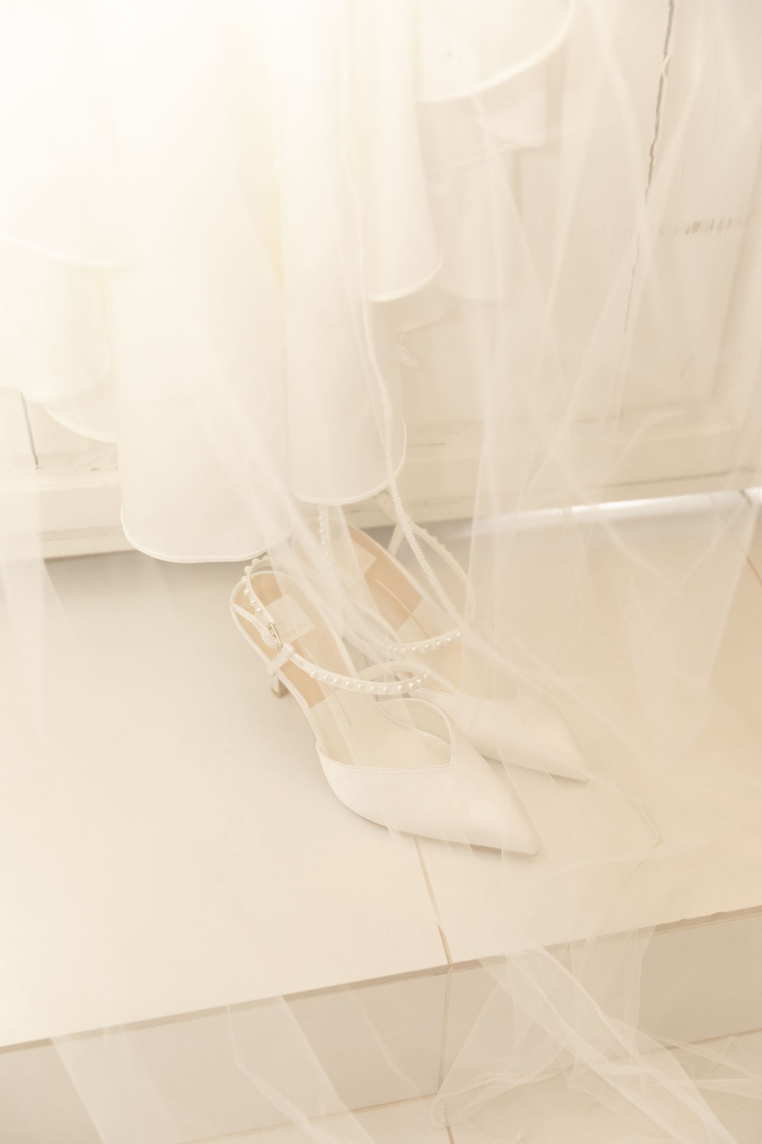 White ballet pointe shoes lined up in a row against a light background with soft ethereal lighting.