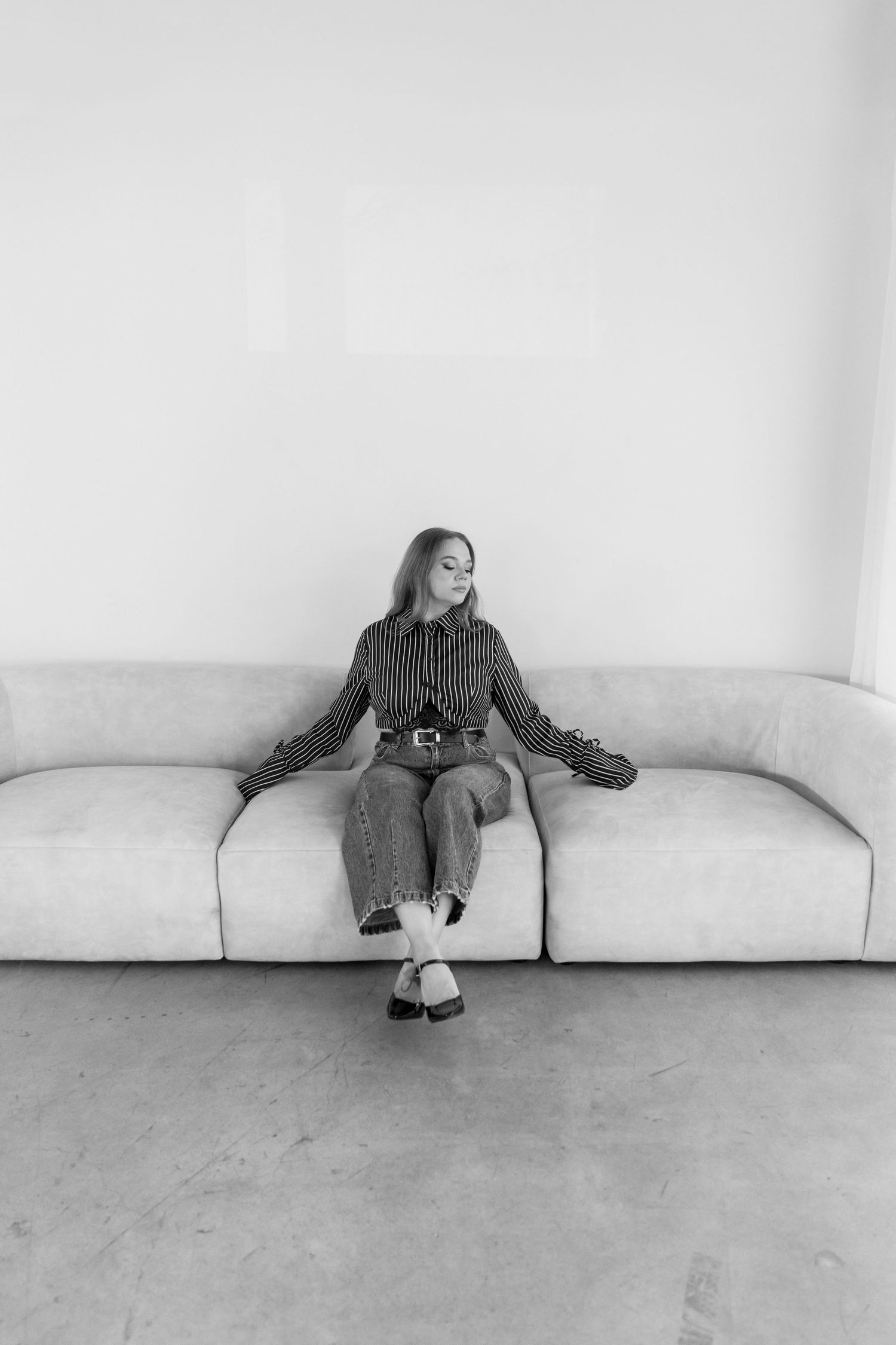 Monochrome photo of a person relaxing on a modern couch against a white wall.