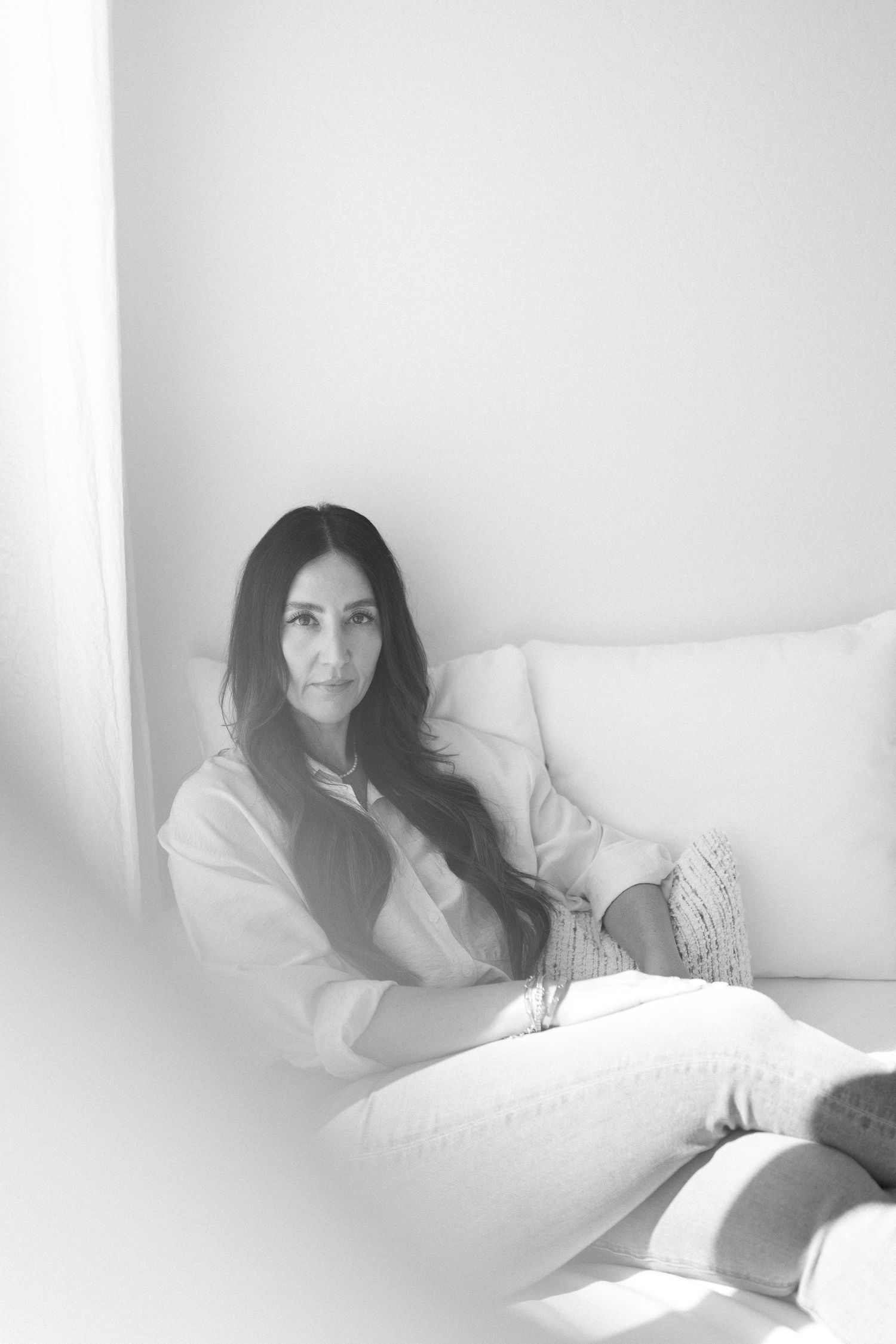 Black and white portrait in minimalist white interior setting.