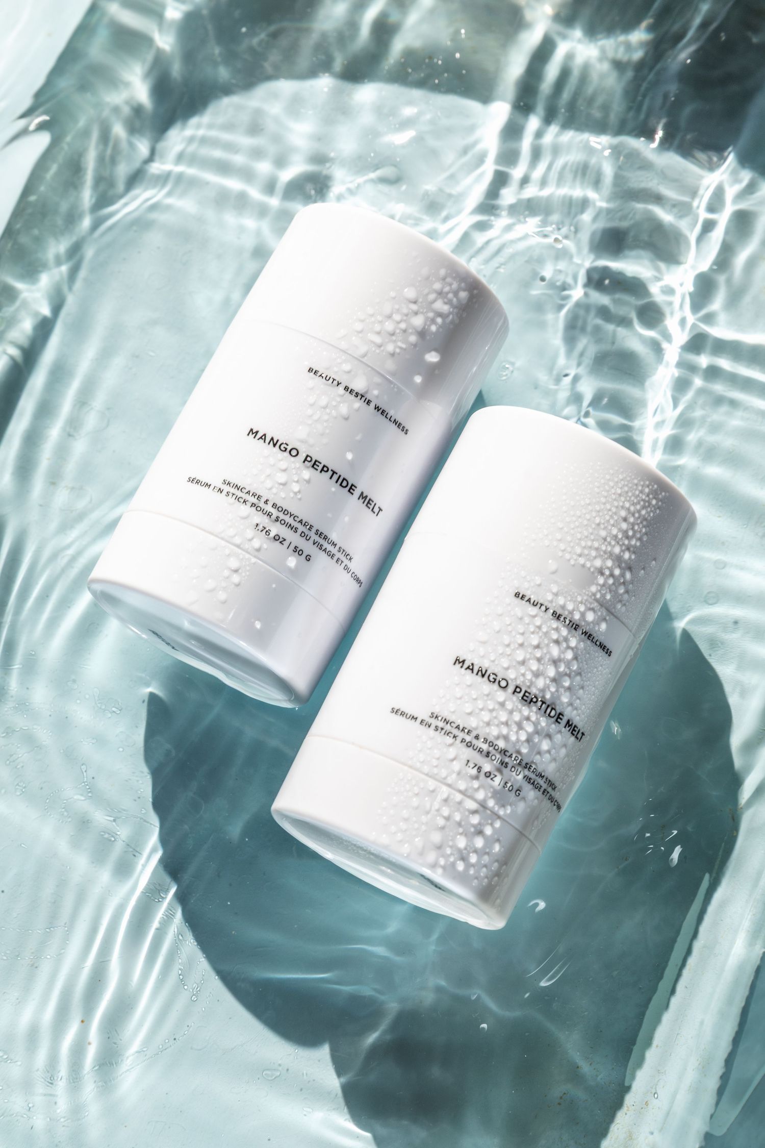A white cosmetic bottle with water droplets floats underwater against a teal-colored backdrop in multiple views.